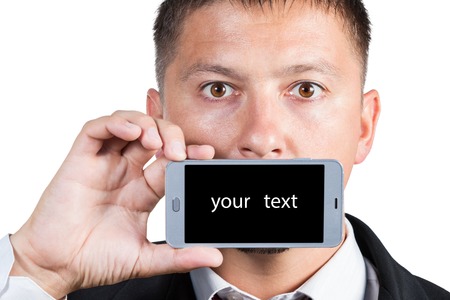 A man in a suit holds a smartphone in one hand with a black screen for your text near the mouth isolated on white backgroundの写真素材