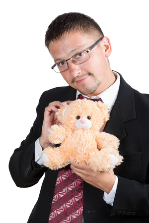 Man in glasses with a mustache and beard, wearing a suit shirt and tie tenderly holding teddy bear isolated on white backgroundの写真素材