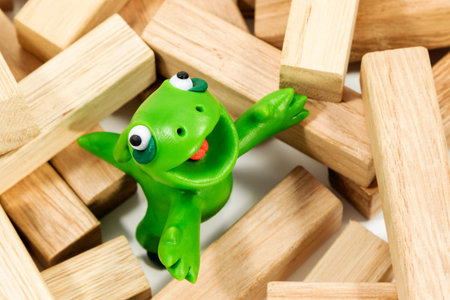 Green plasticine creature looking up standing on a block of woodの写真素材