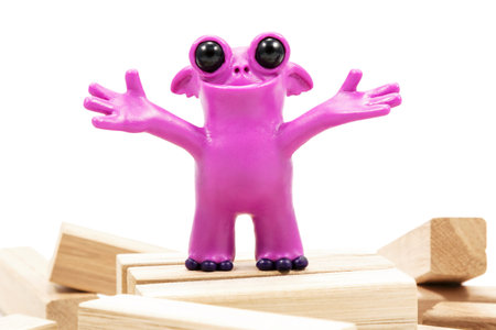 Pink fantastic plasticine monster with a smile on wooden blocks closeup isolated on white backgroundの写真素材