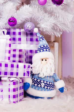 Soft toy Santa Claus with gift boxes under the Christmas tree whiteの写真素材