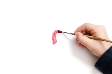 Baby hand makes the brush smear red on the white paperの写真素材