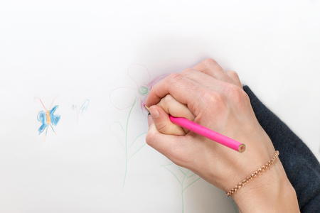 Mom teaches her child to draw holding his hand in her close-upの写真素材