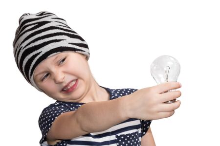 Little child in a cap twisted and looking at the bulb, which holds in his hand isolated on a white backgroundの写真素材