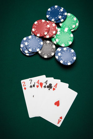 Poker hand of five cards of One-pair on a green table next to chips