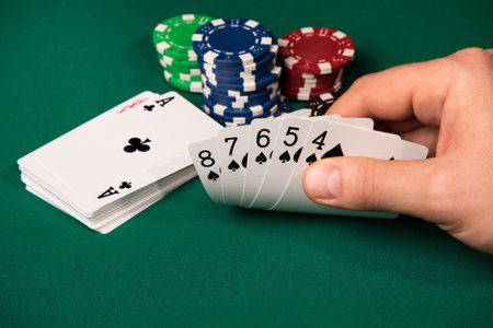 Male hand lifts from the table five cards in a row next to the chips and a deck of cards