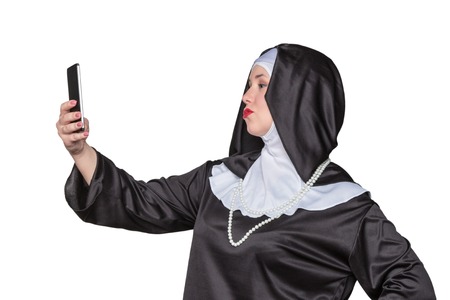 Beautiful nun with bright makeup makes selfie on a smartphone isolated on white backgroundの写真素材