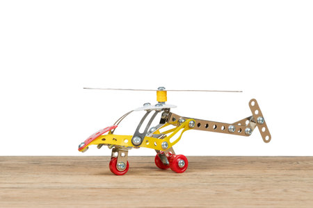 Children helicopter made of iron constructor standing on an old wooden table isolated on white backgroundの写真素材