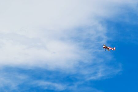 Red and white striped airplane flying in the beautiful blue skyの写真素材