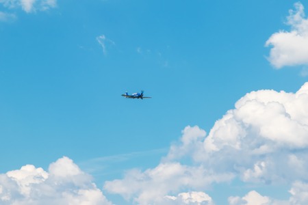 Blue striped plane with propeller flying in blue sky with cloudsの写真素材