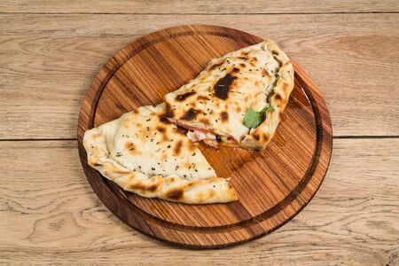 Delicious fried cheburek with leaked oil cut into pieces and served on a wooden plateの写真素材