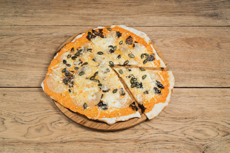 Sweet pizza with pineapple, dried pears and pumpkin seeds, served on a wooden plateの写真素材