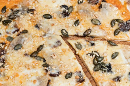Sweet pizza with pineapple, dried pears and pumpkin seeds, served on a wooden plate, closeupの写真素材