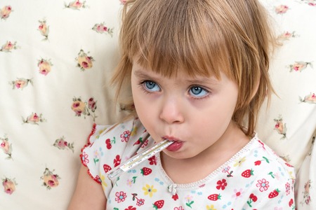 Little blue-eyed child girl with a mercury thermometer in the mouth, closeupの写真素材
