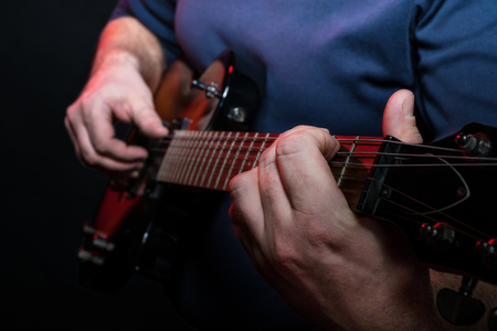 Guitarist playing close-up on electric guitar on a black backgroundの写真素材