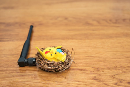 A small antenna connected to the nest with chickens and Easter eggs, lies on a wooden table