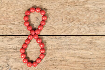 Red wooden beads lined in the form of figures eight on an old wooden tableの写真素材