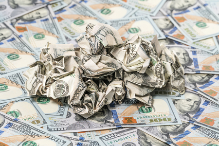 Pile of crumpled money on a background of hundred-dollar billsの写真素材