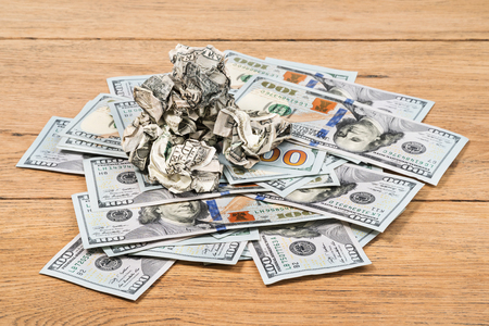Crumpled money on a pile of new dollars lying on an old tableの写真素材