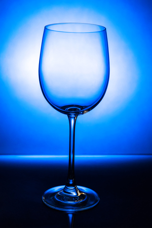 Empty wine glass with reflection on a blue background with a gradient spotの写真素材