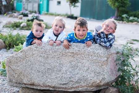 Portrait of four small children lying on a large rockの写真素材