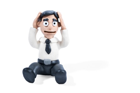 Frustrated plasticine businessman sitting on the floor and holding his head, isolated on white backgroundの写真素材