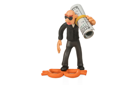 Plasticine bald man with glasses carries on a shoulder roll of dollars and stepped on Bitcoin isolated on white backgroundの写真素材