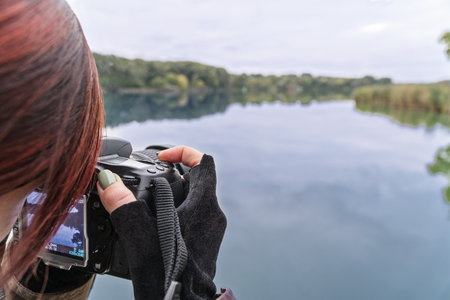 Woman photographer shoots an autumn landscape - a lake with a beach lineの写真素材