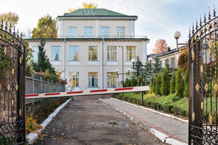 Open forged gates and a closed barrier at the entrance to the house