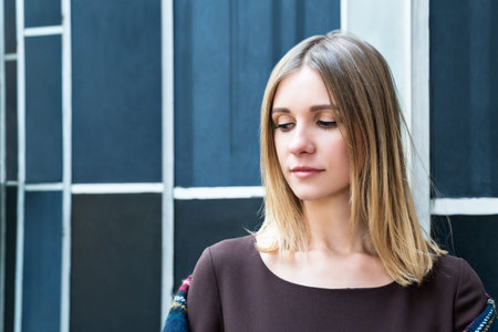Close-up portrait of a beautiful blonde against a blurry city buildingの写真素材