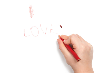 Child hand wrote the word love and broke the lead on the last letter, isolated on white backgroundの写真素材