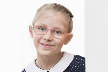 Portrait of a beautiful girl in glasses and a dress in peas on whiteの写真素材