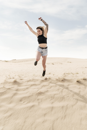 Woman in the desert pushed to jump upの写真素材