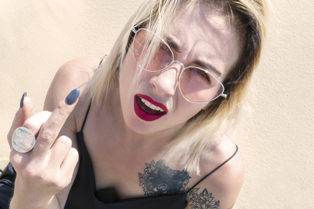 Woman in a dress with a tattoo on his shoulder shows a hand with fuckの写真素材