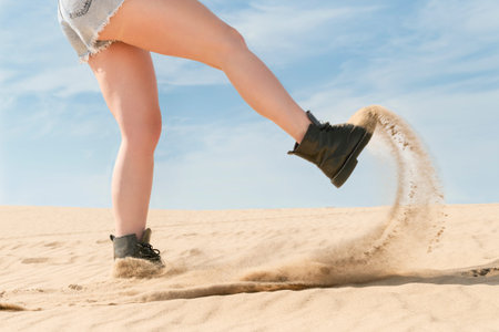 Female foot in the desert hit the sand creating a cloud of dust