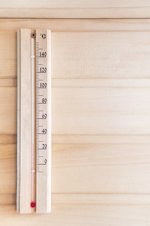 Wooden thermometer showing 28 degrees Celsius on a wooden wallの写真素材