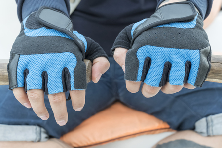 Male hands in blue gloves on old wooden oars, close-upの写真素材