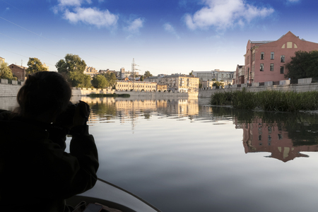 Silhouette of a photographer who photographs a city by the river while sitting in a boatの写真素材
