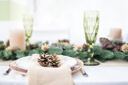 Plate with cones on a table decorated with branches of a Christmas treeの写真素材