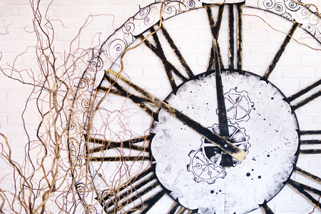 On the wall a large clock with Roman numerals showing at ten minutes to twelveの写真素材