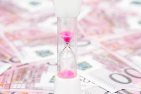 hourglass with pink sand close-up of the euro money