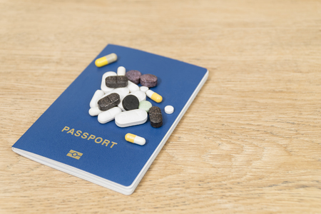 several pills on a biometric passport lying on a wooden tableの写真素材