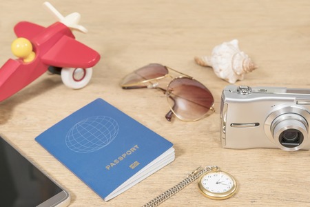 Concept time to go on vacation - toy plane, clock and passport and other items on old wooden boardの写真素材