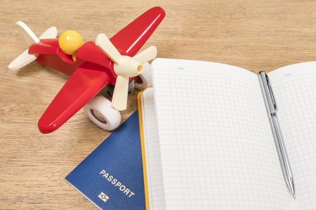 toy plane next to a notebook and passport on an old wooden tableの写真素材