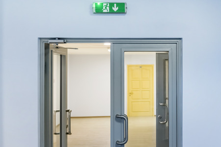 green exit sign above the open door indoorsの写真素材