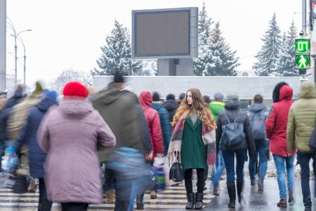 Beautiful woman on a pedestrian crossing among a moving crowdの写真素材