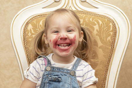 portrait of a little smiling girl with soiled lipstick teeth and faceの写真素材