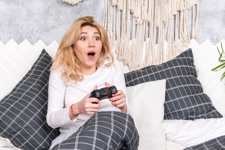 beautiful gambling woman plays the game with the joystick sitting on the bed