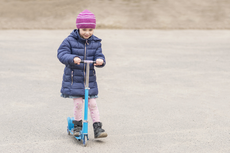 Little beautiful girl rides a scooter on asphaltの写真素材