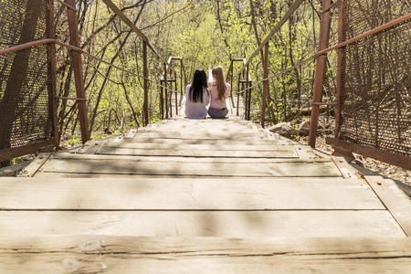 two women sit on the steps back to the camera and point the finger awayの写真素材